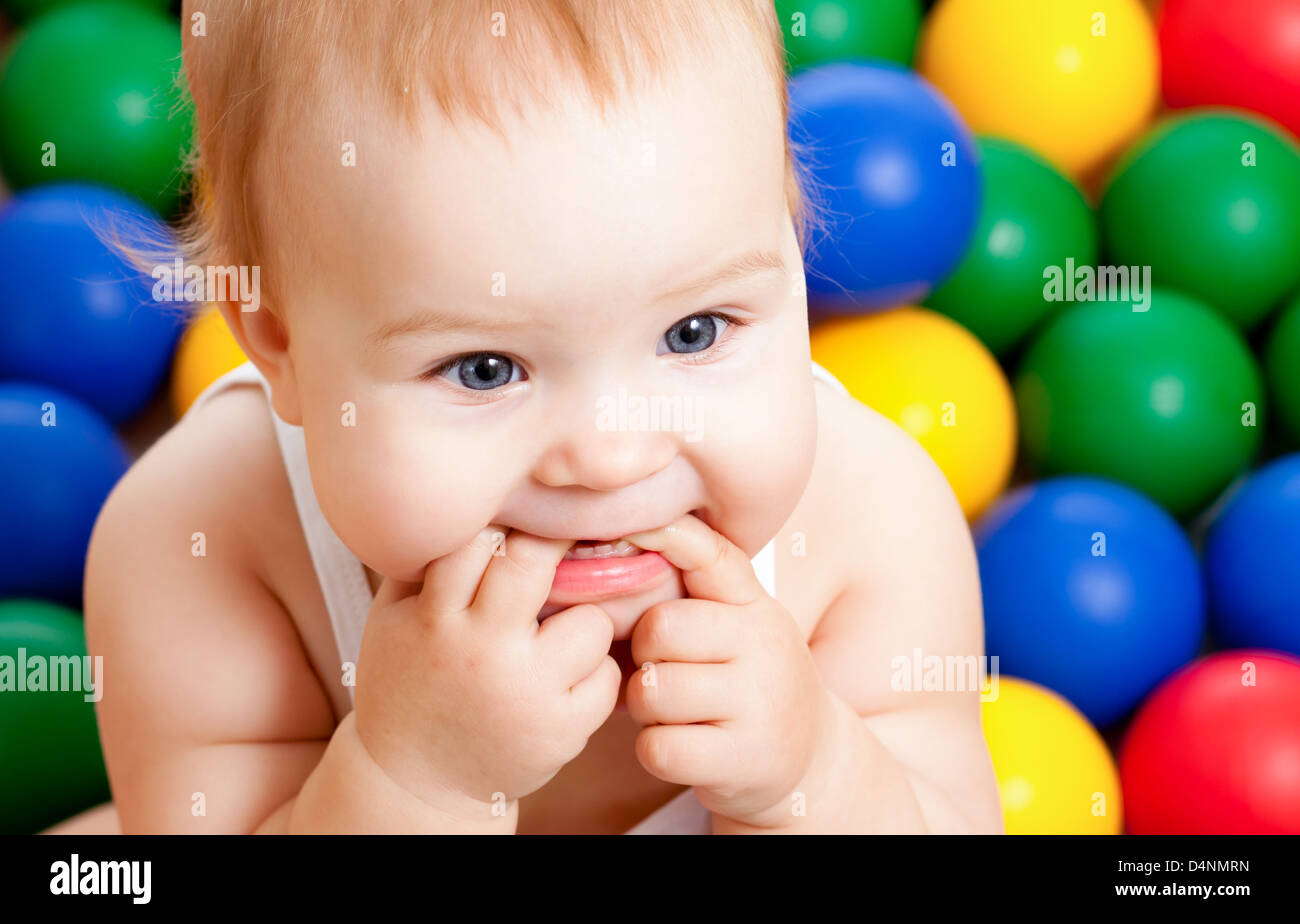 Portrait d'un adorable bébé assis parmi les boules colorées Banque D'Images