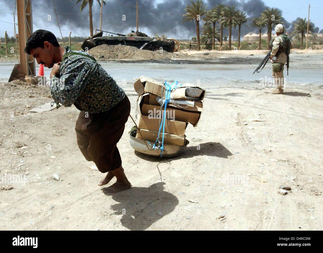Un Irakien tire pillé les appareils ménagers au-delà d'un marine américain le 10 avril 2003 à Bagdad. Banque D'Images