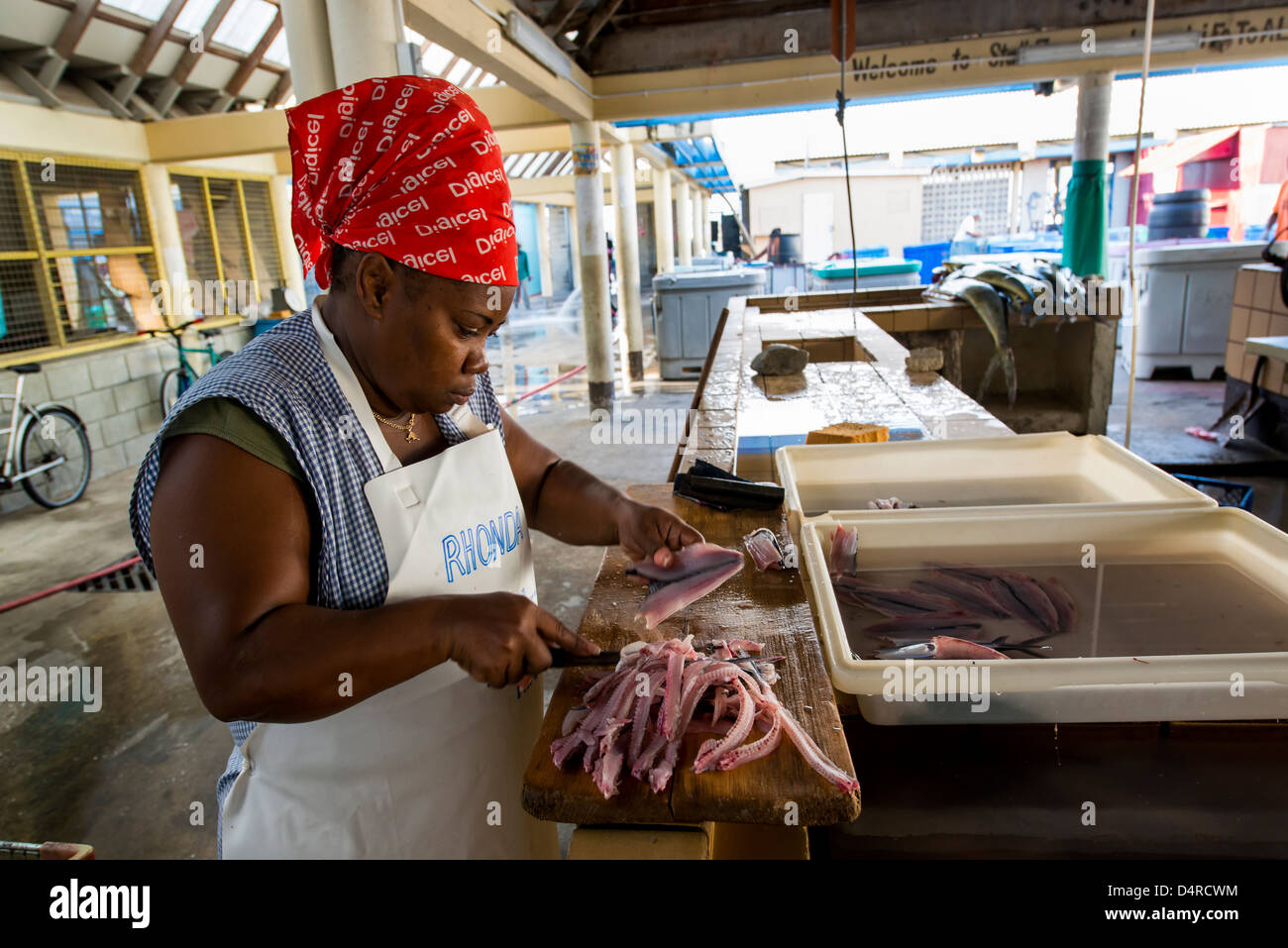 Une femme de courage des poissons volants dans le marché aux poissons de Bridgetown, Barbados, Caribbean Banque D'Images