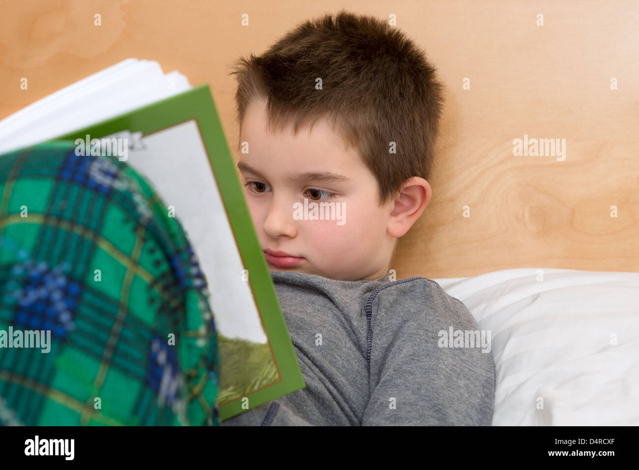 La lecture de temps de lit en pyjama ; huit ans kid lire son livre avant de dormir. Banque D'Images