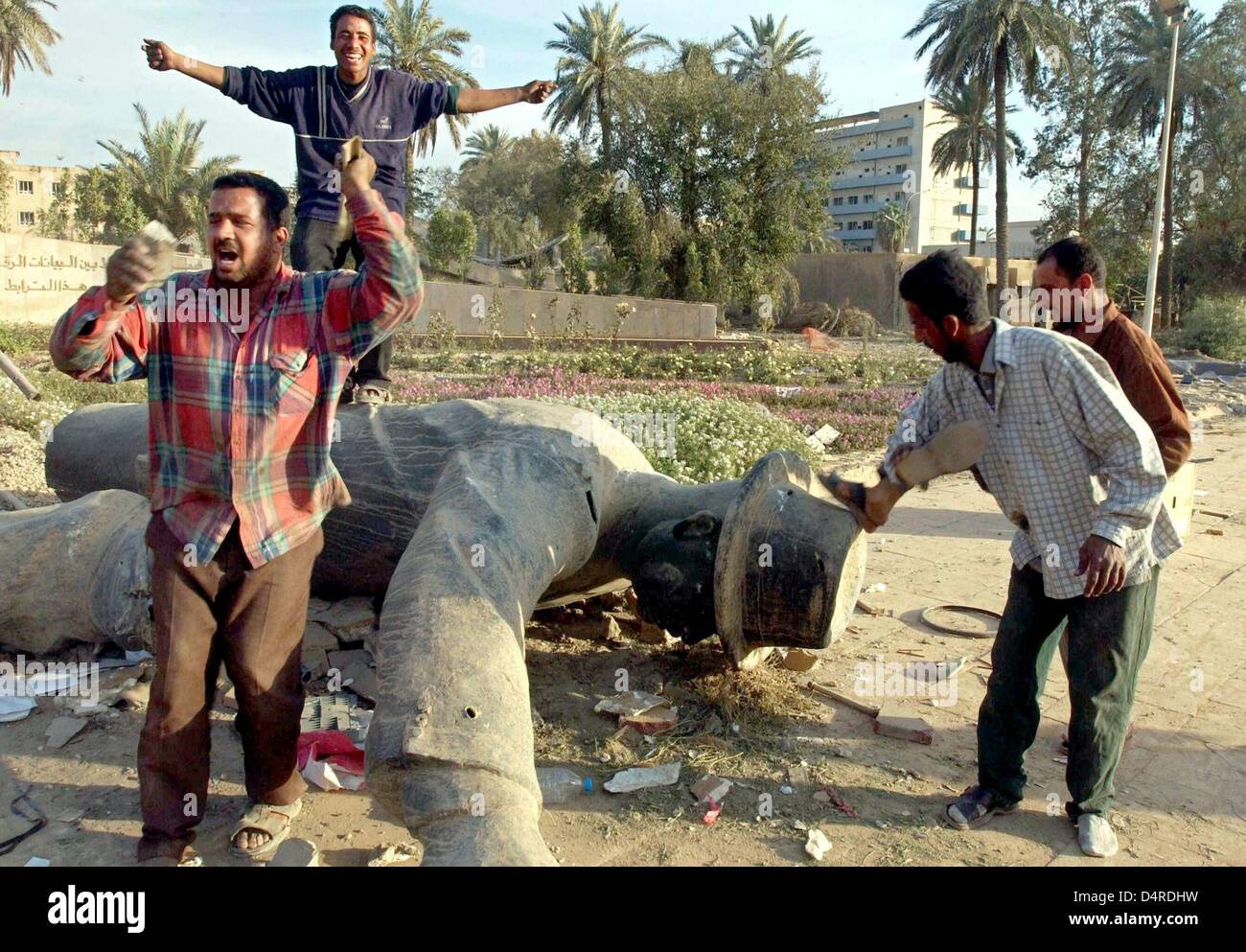 Les iraquiens sont cheering in front of a fallen statue de Saddam Hussein le 12 avril 2003 à Bagdad. Banque D'Images