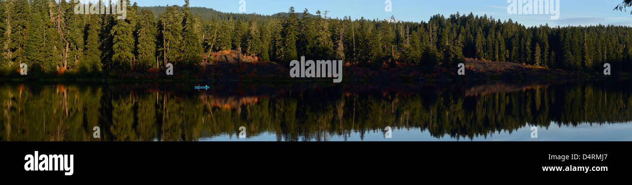 Pêche à la ligne d'un canot au milieu de l'automne réflexions sur Clear Lake dans l'Oregon est des Cascades. Banque D'Images