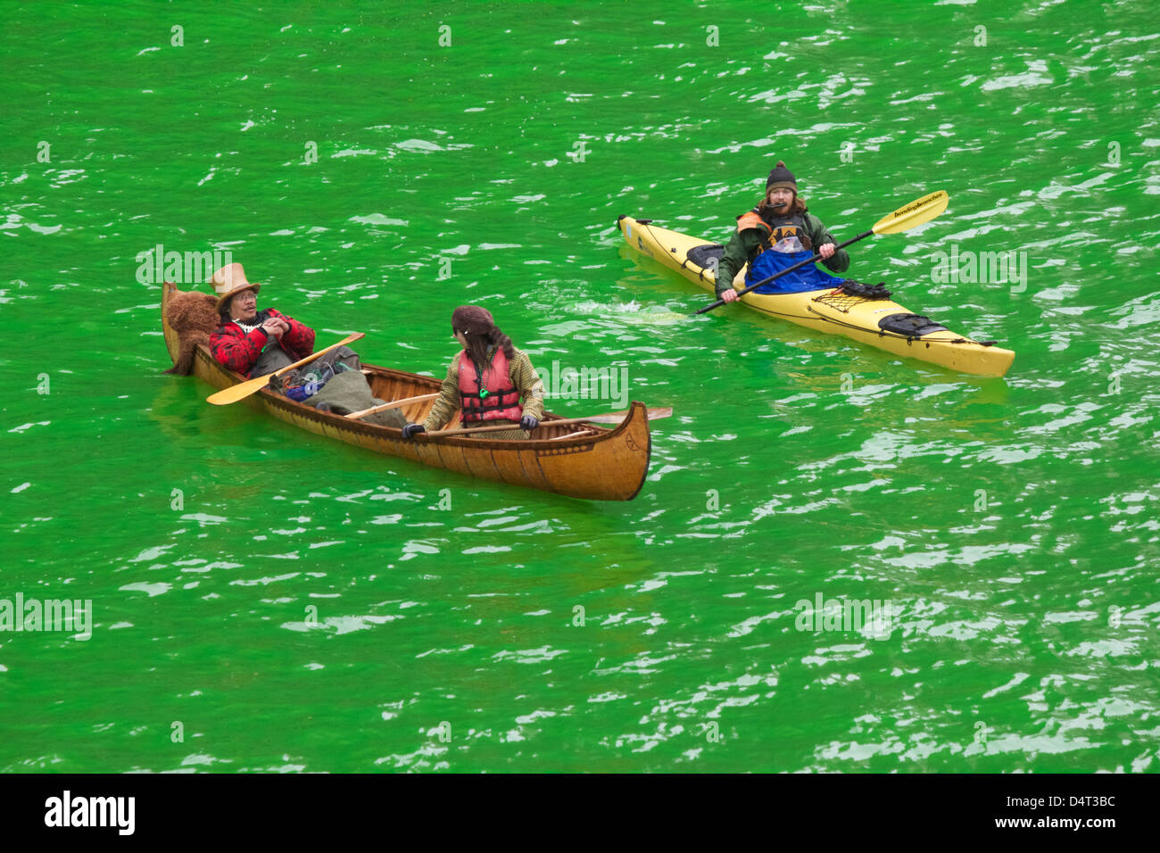 Les canoteurs et kayakistes à Chicago River teint en vert pour la Saint-Patrick. La kayakiste a cell phone en bouche. Banque D'Images