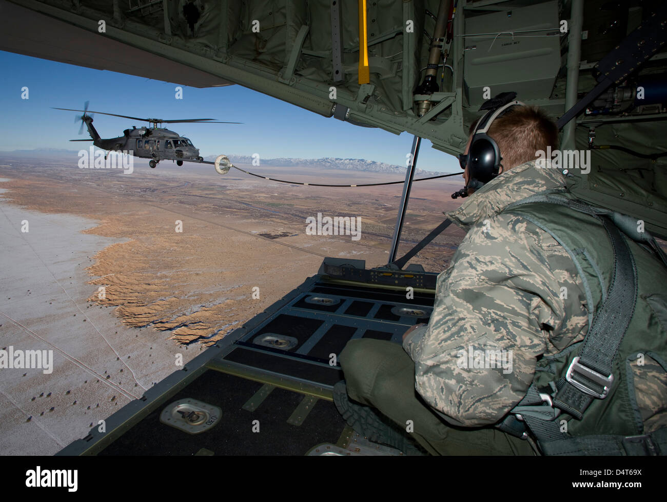Arrimeur sur un HC-130 regarde un HH-60G Pave Hawk ravitaille. Banque D'Images