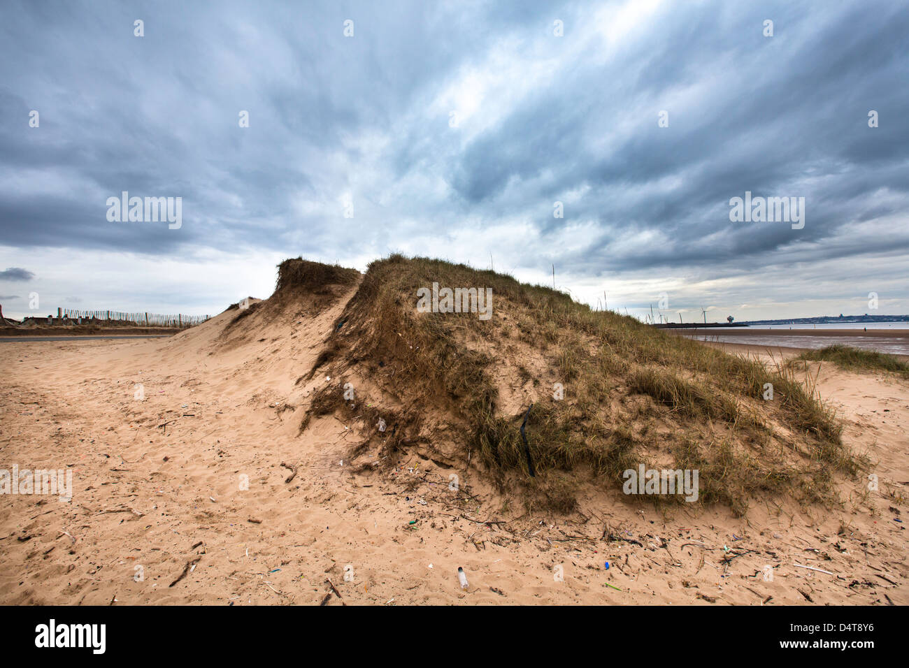 Colline de sable avec de l'herbe sur une plage avec des nuages dynamiques Banque D'Images