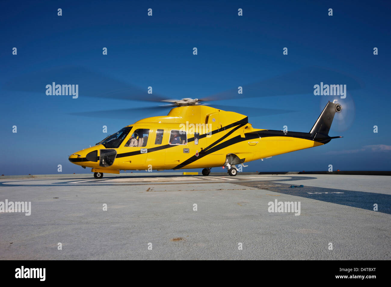 Un hélicoptère Sikorsky S-76 utility se prépare à décoller d'une plate-forme pétrolière. Banque D'Images