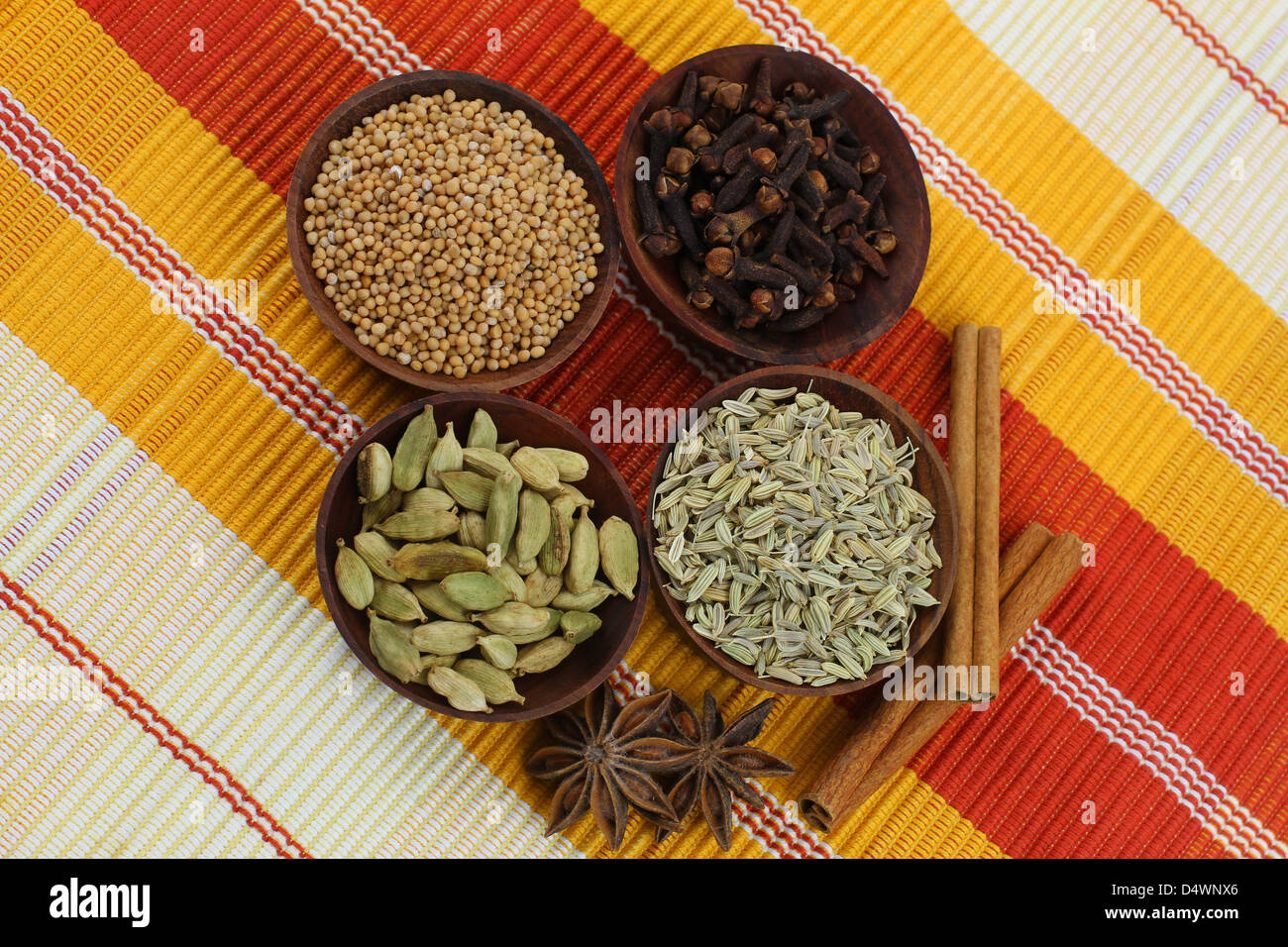 Les épices mélangées dans de petits bols en bois sur fond rayé Banque D'Images