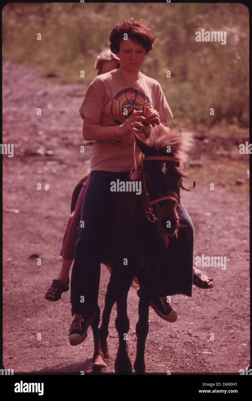 Donna Smith, 16 ans, fille de Jack Smith, un mineur handicapé, de Rhodell, près de Beckley, Virginie occidentale, se déplace le poney familial avec un voisin assis derrière son 06/1974 Banque D'Images