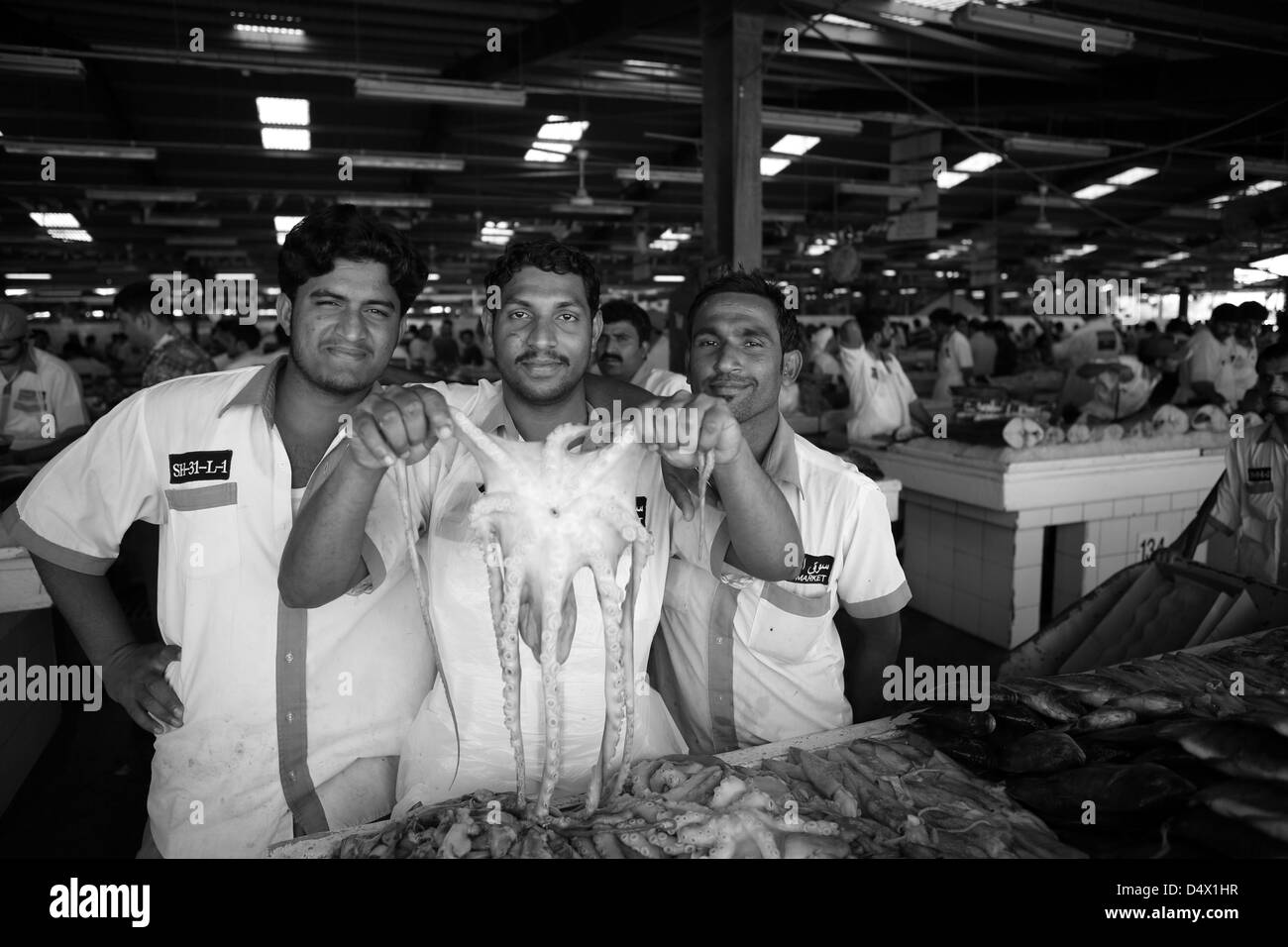 Groupe d'hommes au marché de poisson holding up poulpe, Dubai, Émirats Arabes Unis Banque D'Images