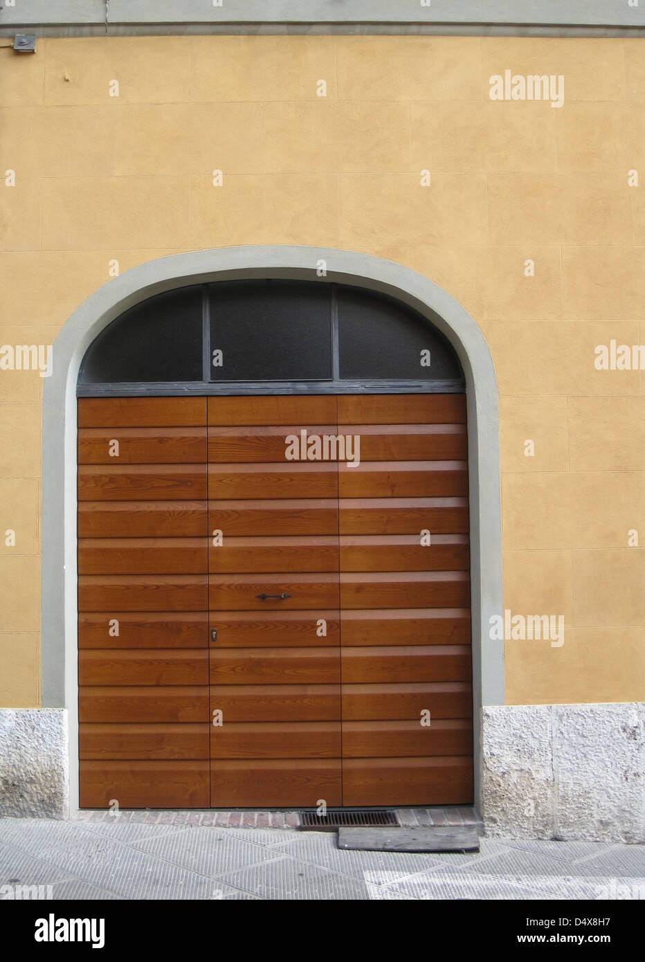 Rayé, contemporain, porte de garage en bois sur une maison de stuc jaune sur une rue étroite à Sienne, Toscane, Italie Banque D'Images