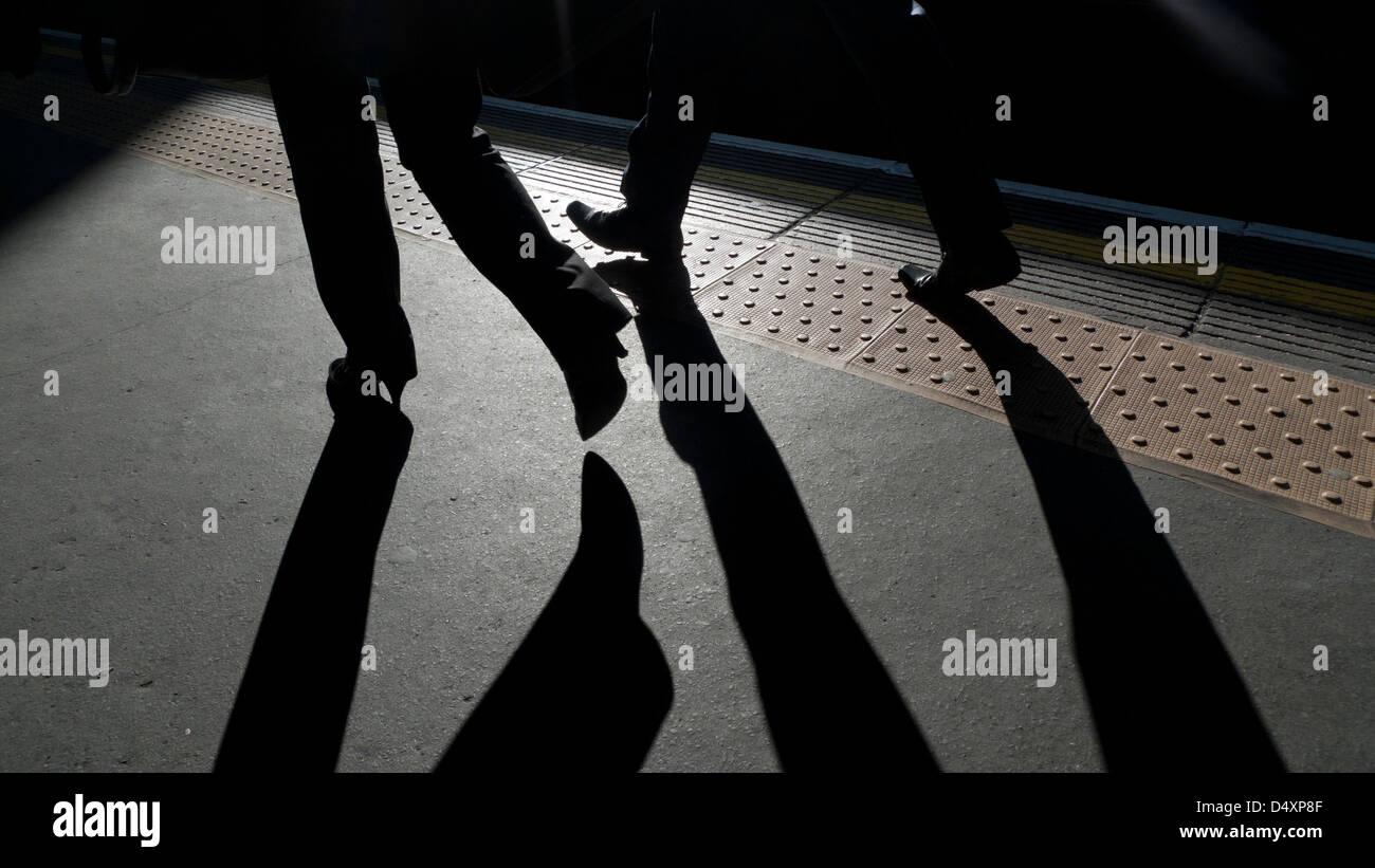 Les travailleurs de bureau de navetteurs jambes ombre ombres personnes marchant le long du bord de la plate-forme de métro Barbican station à Londres Angleterre KATHY DEWITT Banque D'Images