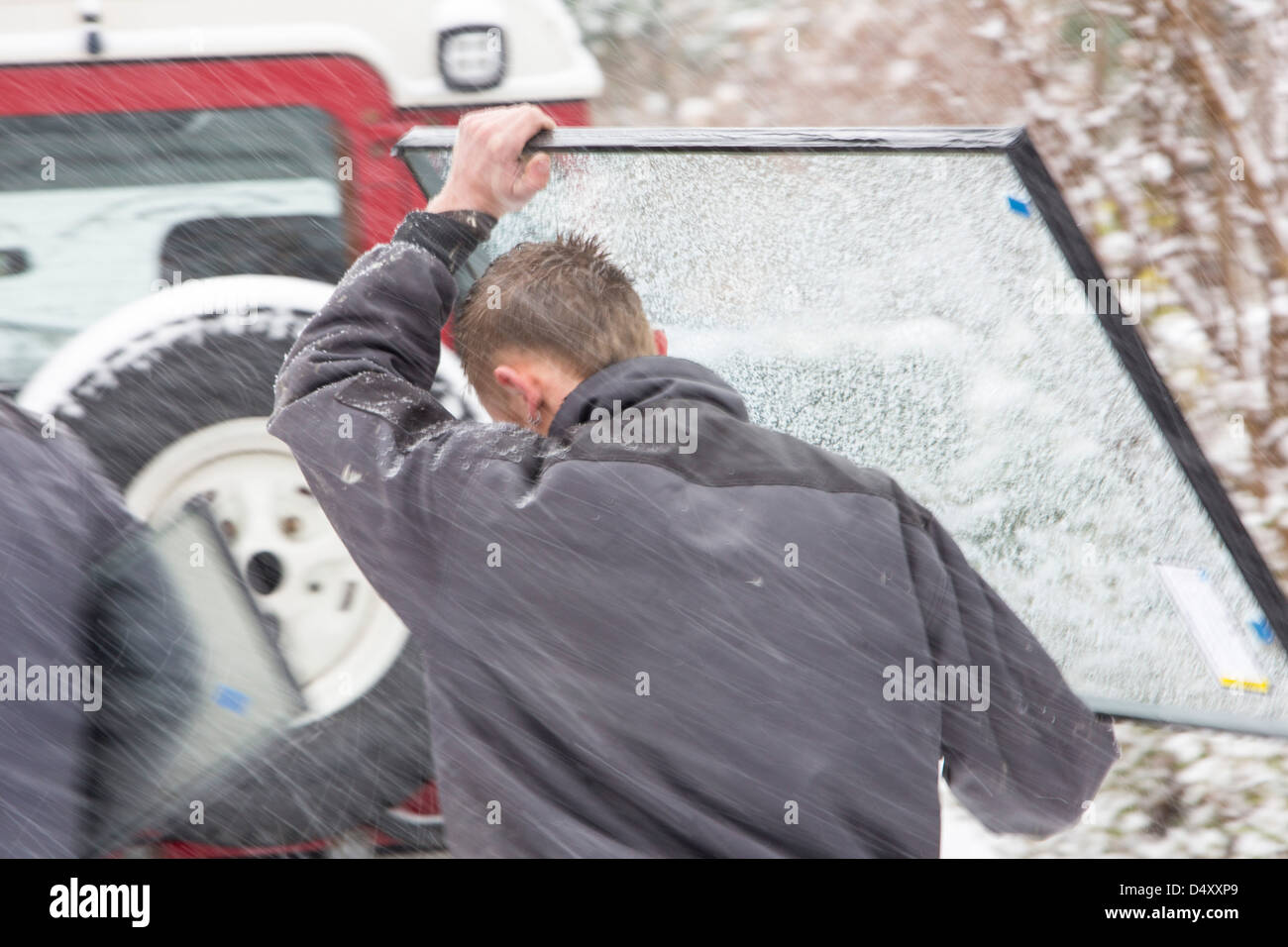 Vitriers exerçant son activité sous une sous-fenêtre dans la neige après leur van est resté coincé sur une colline raide, Ambleside, Lake District, UK. Banque D'Images