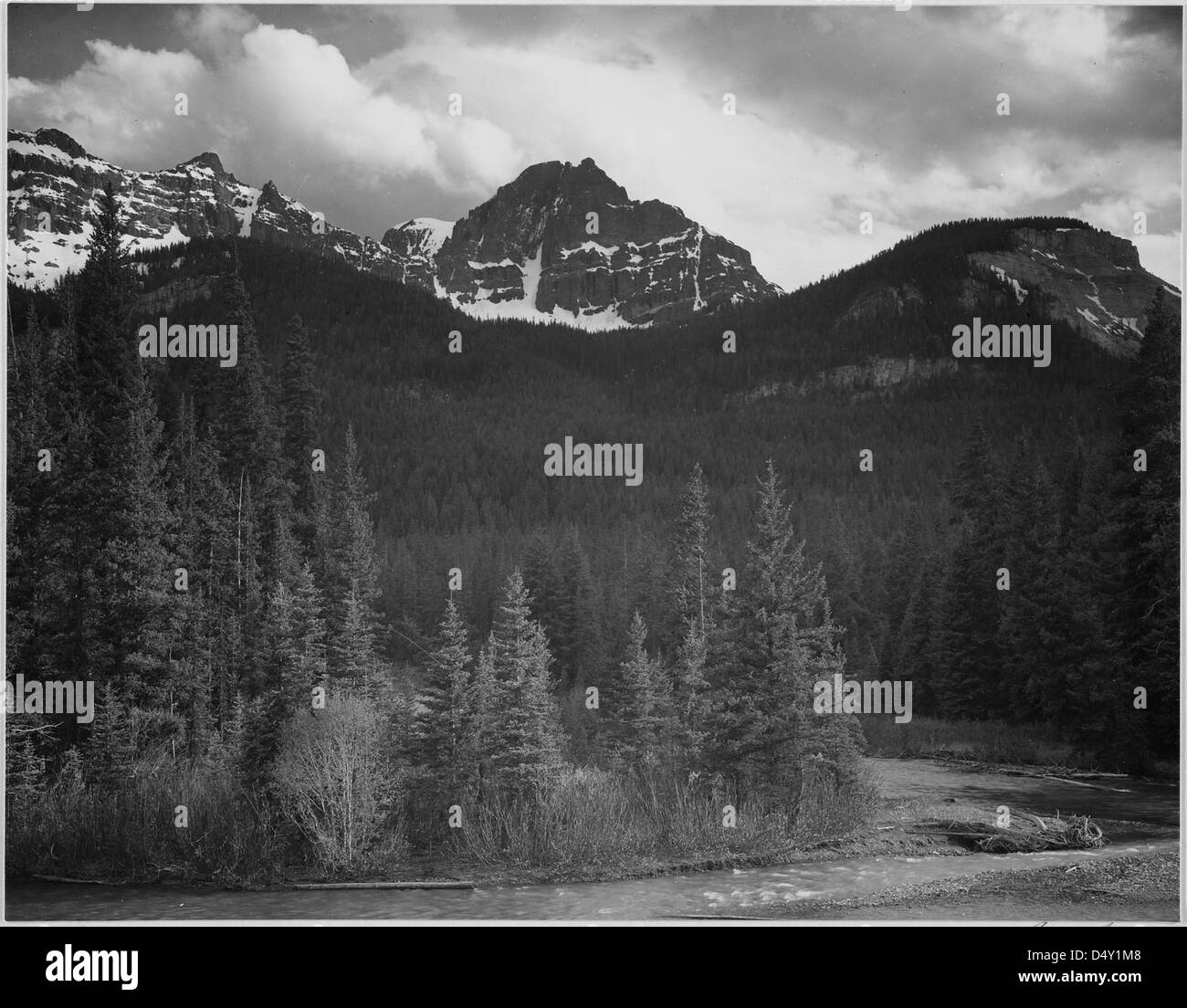 Cette photographie d'Ansel Adams montre un ruisseau au premier plan avec des montagnes enneigées dans le parc national de Yellowstone, Wyoming. L'image capture la beauté naturelle et le paysage serein de la partie nord-est du parc. Banque D'Images