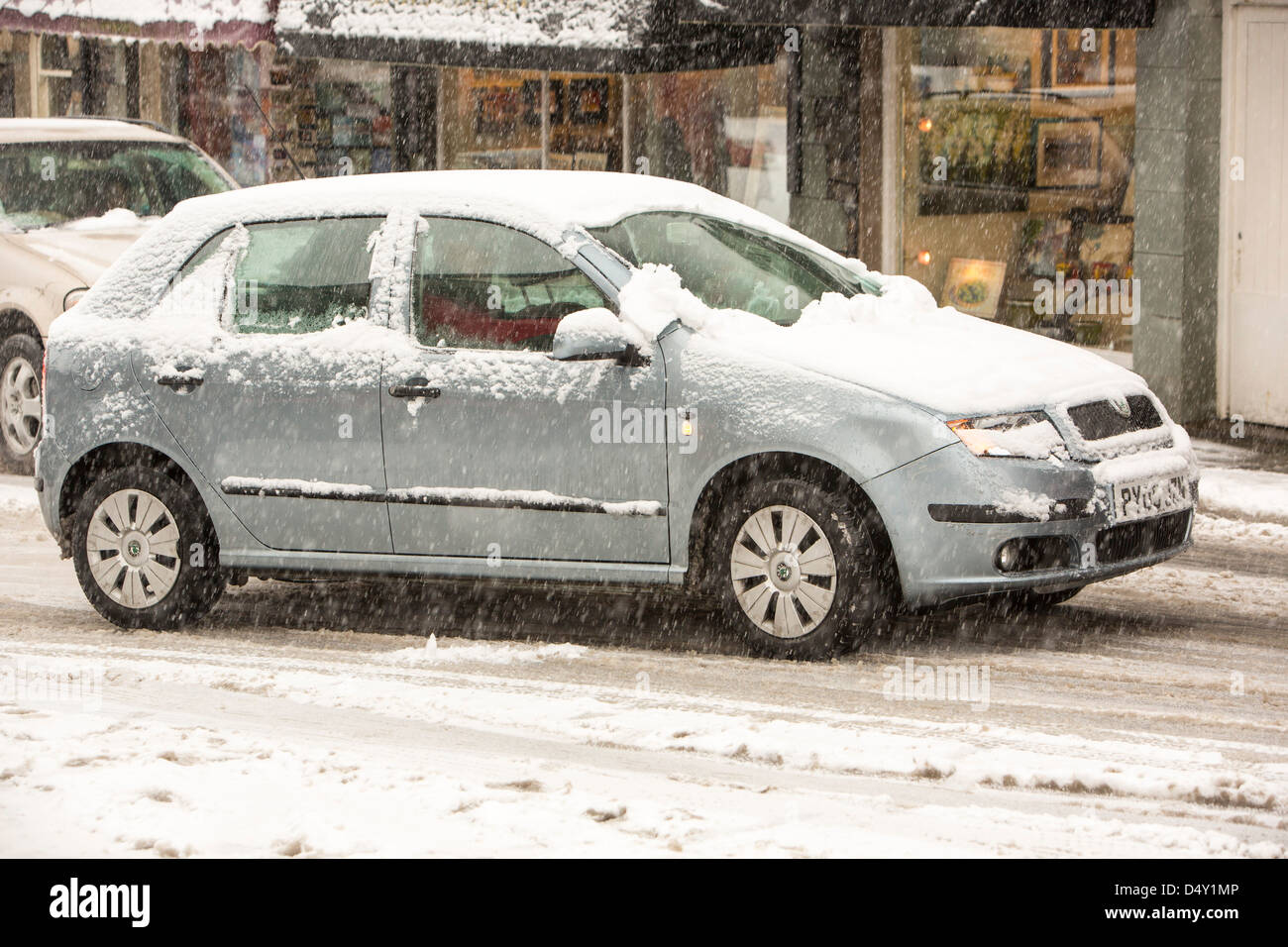 Les voitures qui circulent dans Ambleside dans la neige, Lake District, UK. Banque D'Images