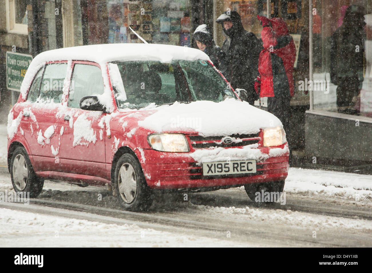 Les voitures qui circulent dans Ambleside dans la neige, Lake District, UK. Banque D'Images