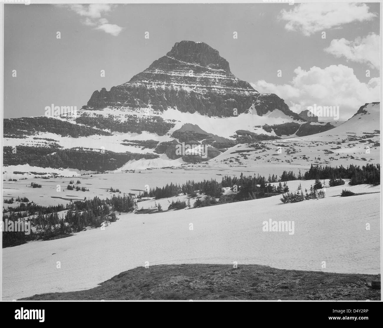 La photographie emblématique en noir et blanc d'Ansel Adams capture le paysage aride depuis Logan Pass dans le parc national des glaciers, avec des montagnes enneigées et des panoramas spectaculaires. L'image met en valeur la beauté sauvage du parc. Banque D'Images
