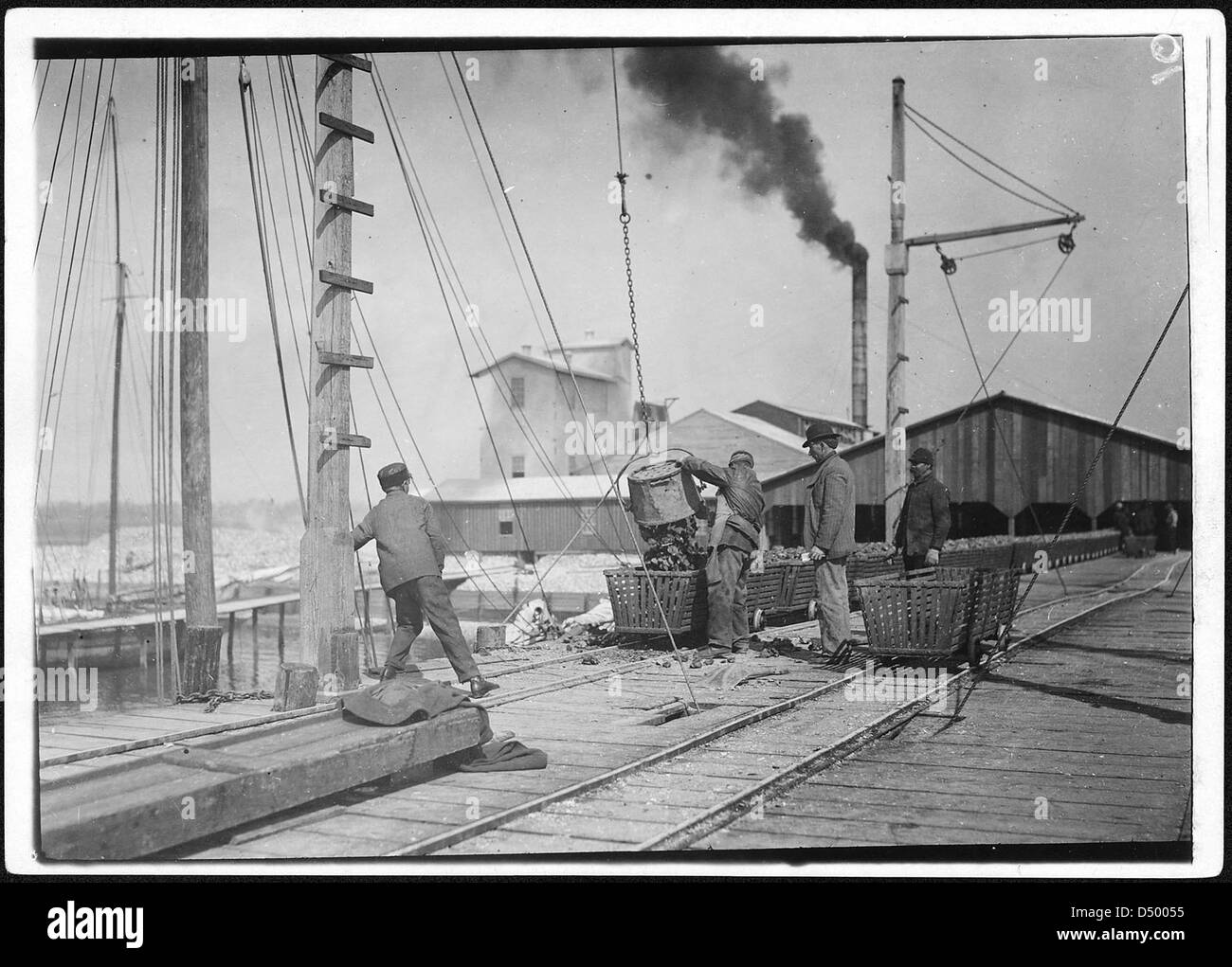Ouvriers déchargeant des huîtres à Alabama Canning Co. À Bayou la Batre, Alabama, février 1911. Cette photographie de Lewis Hine documente les conditions de travail de l'industrie des fruits de mer du début du XXe siècle. Banque D'Images