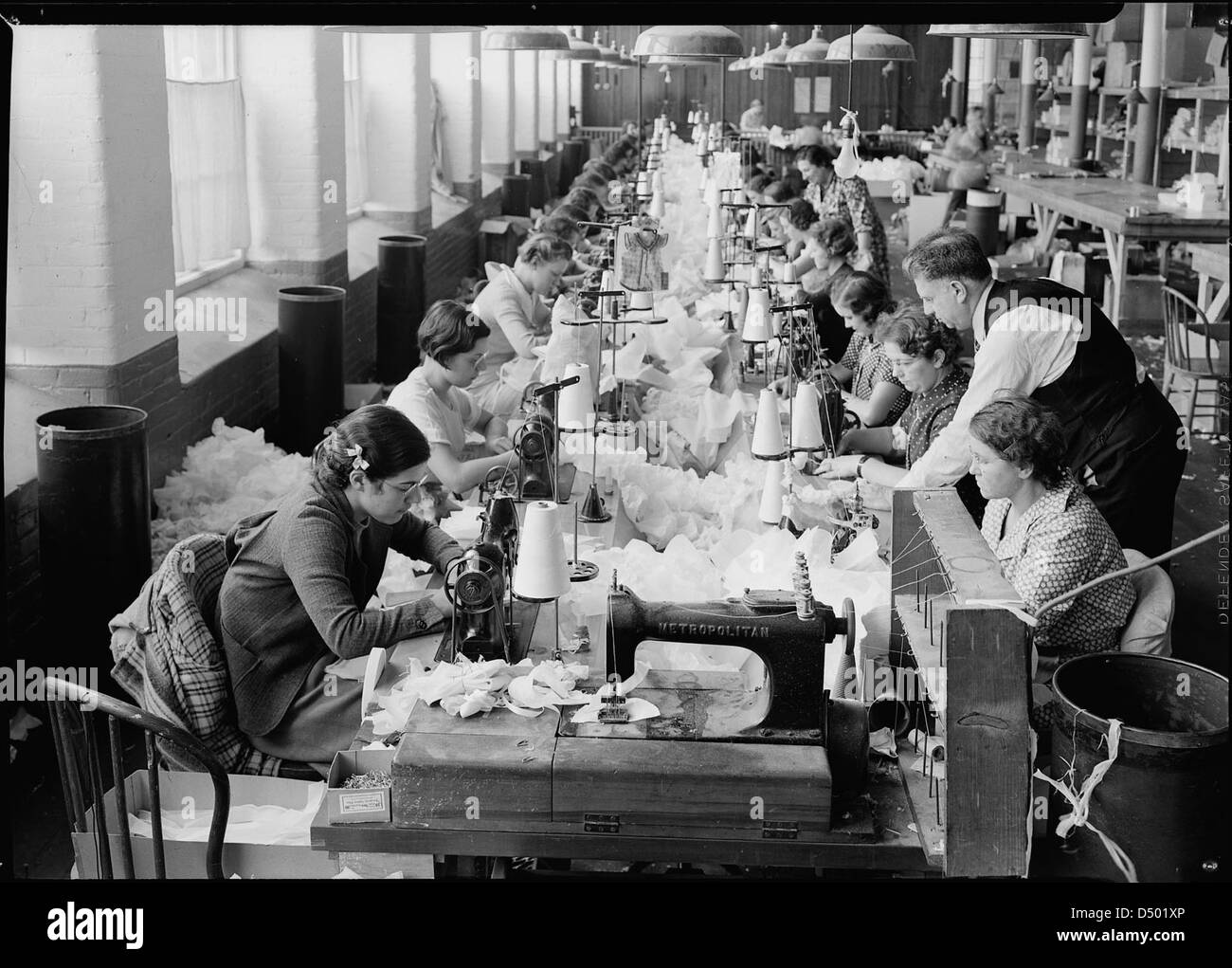 Une photographie de 1936 montre un groupe travaillant avec des machines à coudre électriques Singer à la Paragon Rubber Company à Mt. Holyoke, Massachusetts. L'image met en évidence la production de personnages américains Dolls pendant la Grande dépression, capturée par Lewis Hine. Banque D'Images