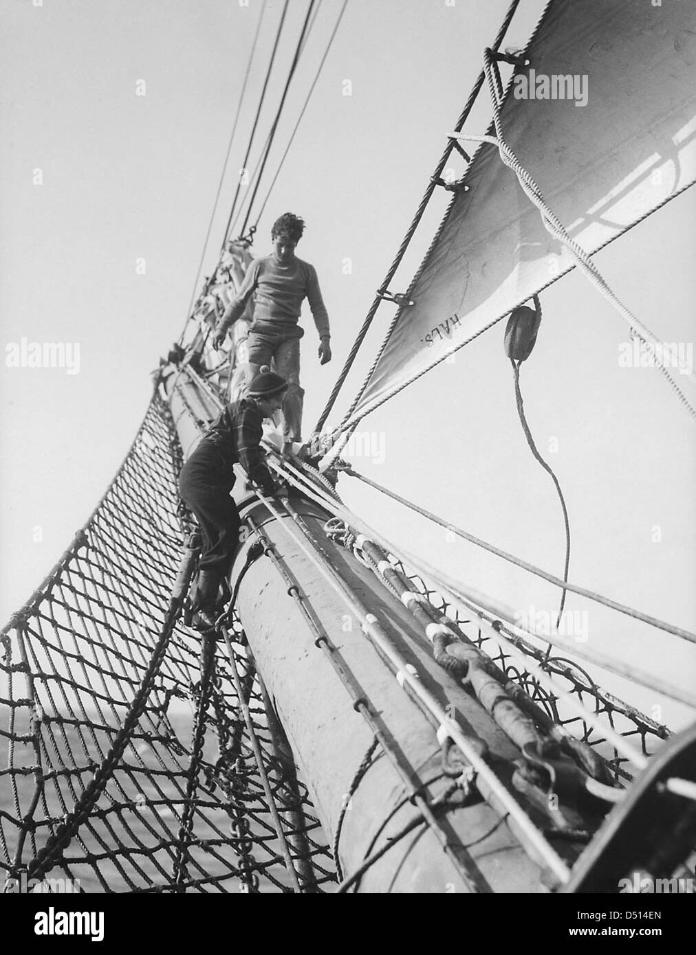 Cette image montre un membre de l'équipage debout sur l'intestin du 'Parme', un navire historique, présentant la tenue nautique classique et le bateau à voile traditionnel. Banque D'Images