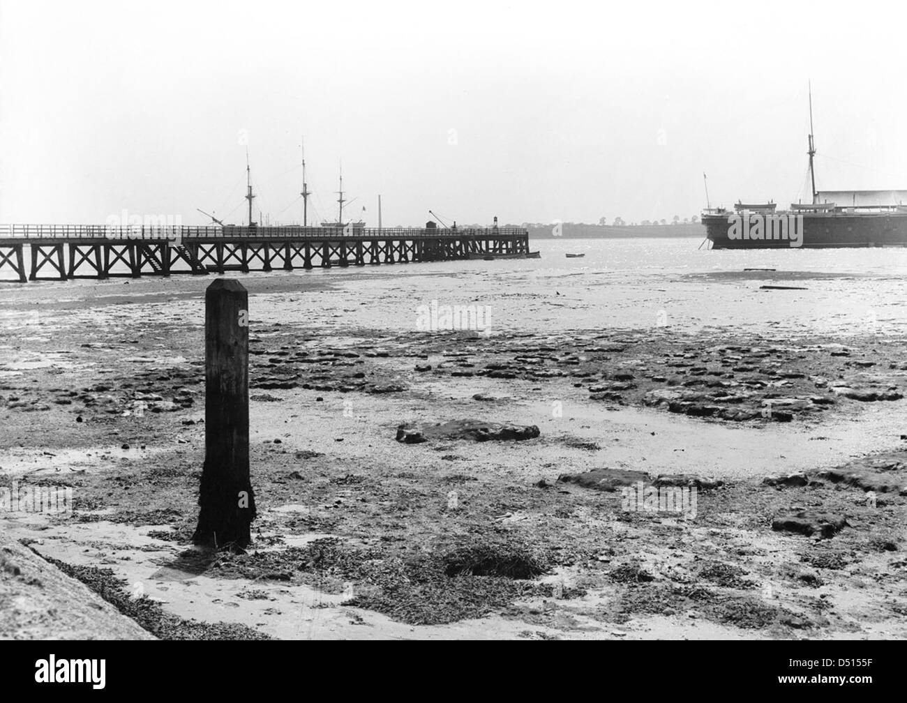 Cette photographie capture une vue du rivage vers Shotley Pier à marée basse, offrant une représentation paisible du paysage et des infrastructures maritimes. Banque D'Images