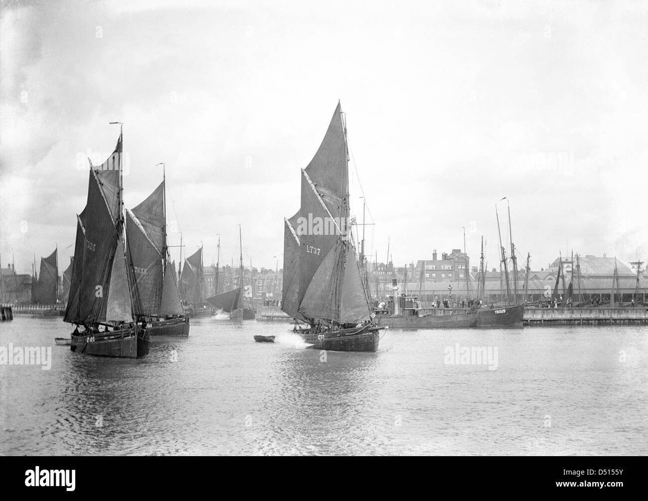 Une photographie montrant les chalutiers à voile LT325, LT653 et LT37 quittant le port extérieur, capturée depuis le brise-lames. Ces navires représentent des techniques de pêche traditionnelles dans l'histoire maritime du Royaume-Uni. Banque D'Images