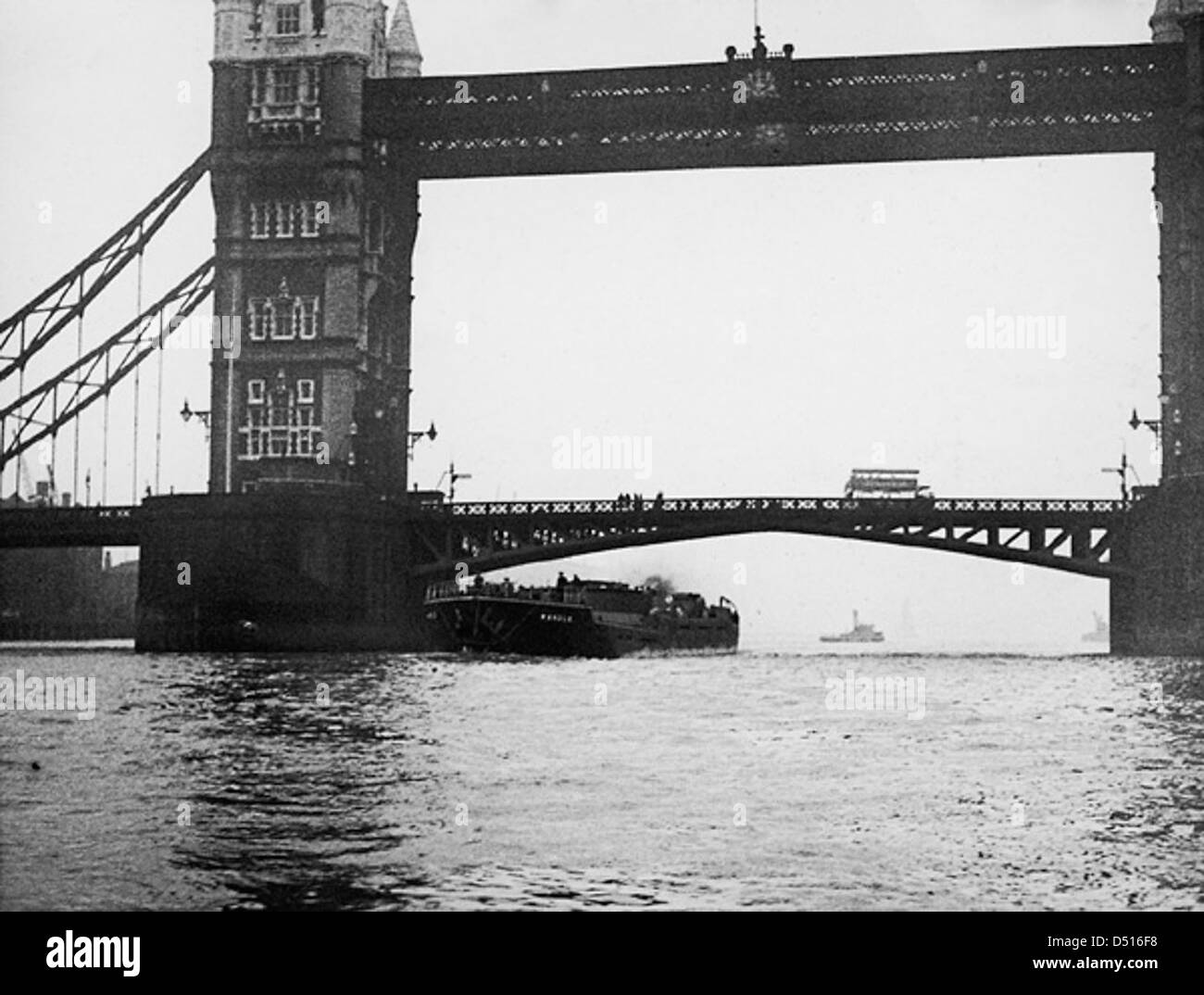 Le SS « Wandle », un bateau à vapeur, passe sous l'emblématique Tower Bridge à Londres. Cette image historique capture un moment important de l’histoire maritime, puisque le pont s’ouvre pour permettre le passage du navire. Tower Bridge, symbole de Londres, est connu pour son design remarquable et son rôle dans l'infrastructure de la ville. Banque D'Images