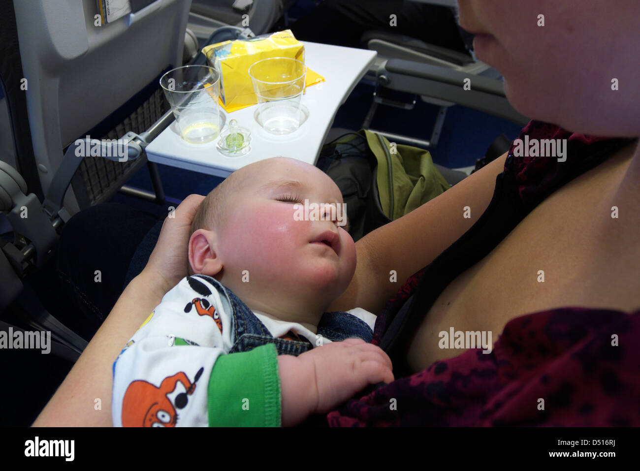 Un Jeune 8 Mois Bebe Endormi Dans Ses Bras Les Meres Dans Un Avion Photo Stock Alamy