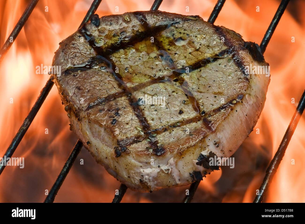 Le bifteck sur le grill bar rayé fiery closeup Banque D'Images