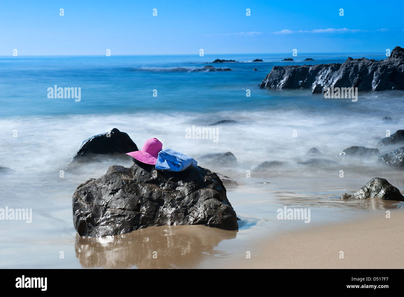 Une plage goer's chapeau rose et la serviette reste sur un rocher le long d'une plage dans le sud de la Californie. Banque D'Images