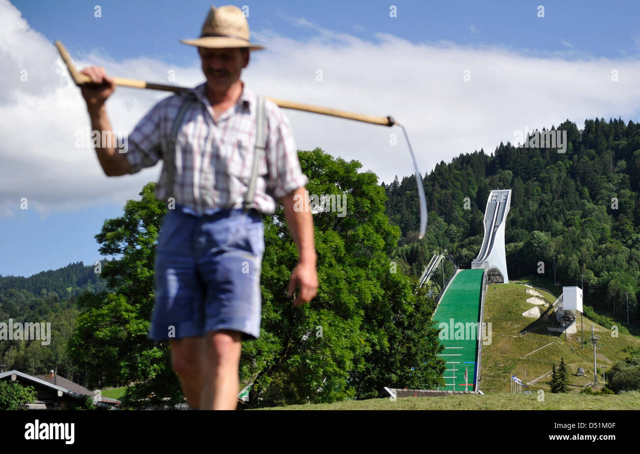 Faucille dans la main, un agriculteur quitte les Jeux Olympiques saut à ski hill à Garmisch-Partenkirchen, Allemagne, 09 août 2010. Après leur ultimatum à Munich's Olympia demandeurs a manqué, 59 propriétaires fonciers ont abordé le Cimittee International Olympique (CIO) directement, en indiquant qu'ils n'aurait pas de leurs terres disponibles pour les Jeux Olympiques d'hiver de 2018. Photo : Marc Mueller Banque D'Images