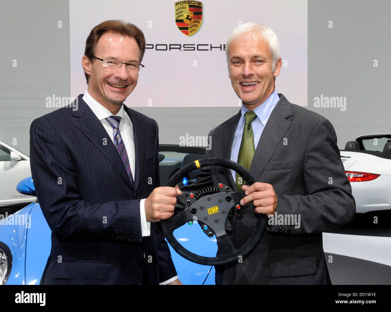 Michael Macht (L), le président de Porsche les mains sur un volant à son successeur Matthias Mueller au Paris Motor Show 'Mondial de l  Automobile' à Paris, France, 30 septembre 2010. L'Automobile de Paris se tient tous les deux ans et est l'une des plus grandes présentations de véhicules à moteur dans le monde. Cette année, l'accent de la série se trouve sur les voitures électriques et plus de 30 Banque D'Images