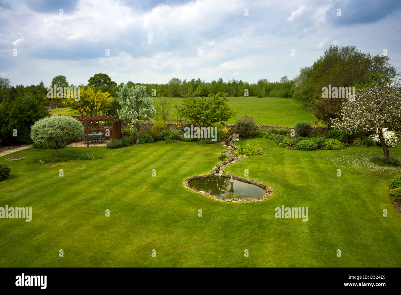 UK gardens. Un grand jardin avec pelouse avec faucheuse bandes et la campagne au-delà. Banque D'Images