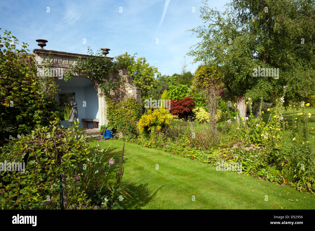 UK gardens. Un jardin mature avec parterres, arbres, arbustes d'une période d'architecture grotto. Banque D'Images