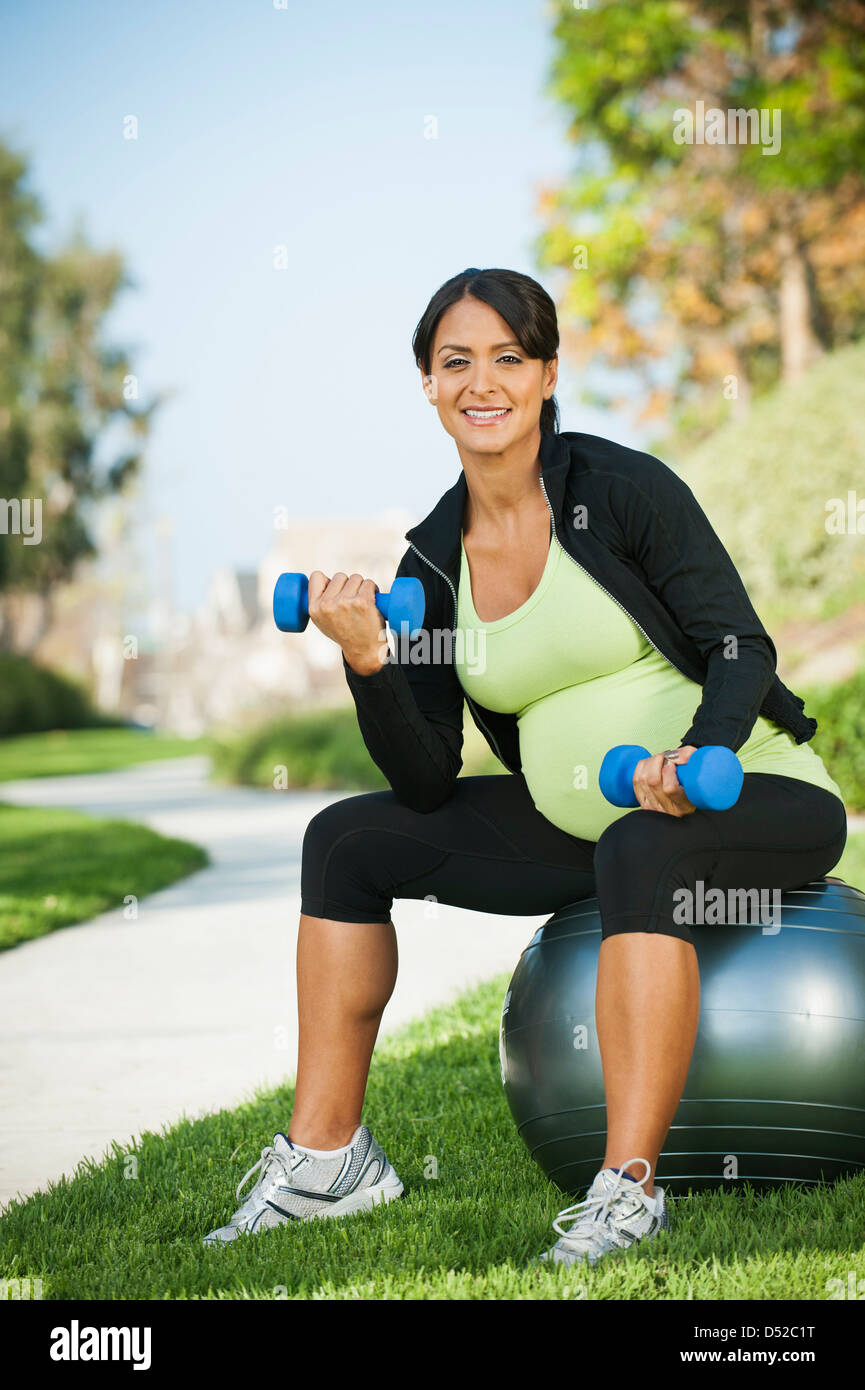 Pregnant Hispanic woman lifting weights outdoors Banque D'Images