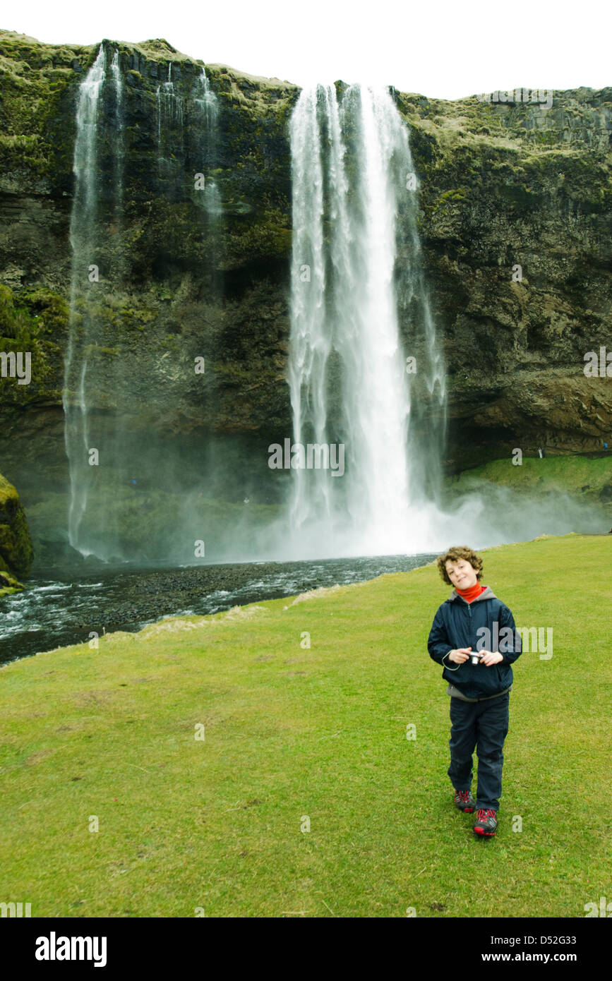 Smiling boy posant devant une cascade, l'Islande Banque D'Images