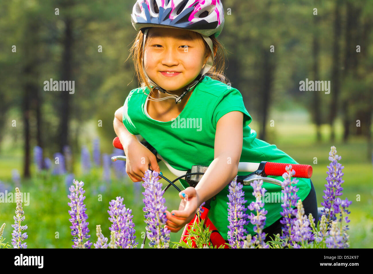 Asian girl sitting on bicycle in meadow Banque D'Images