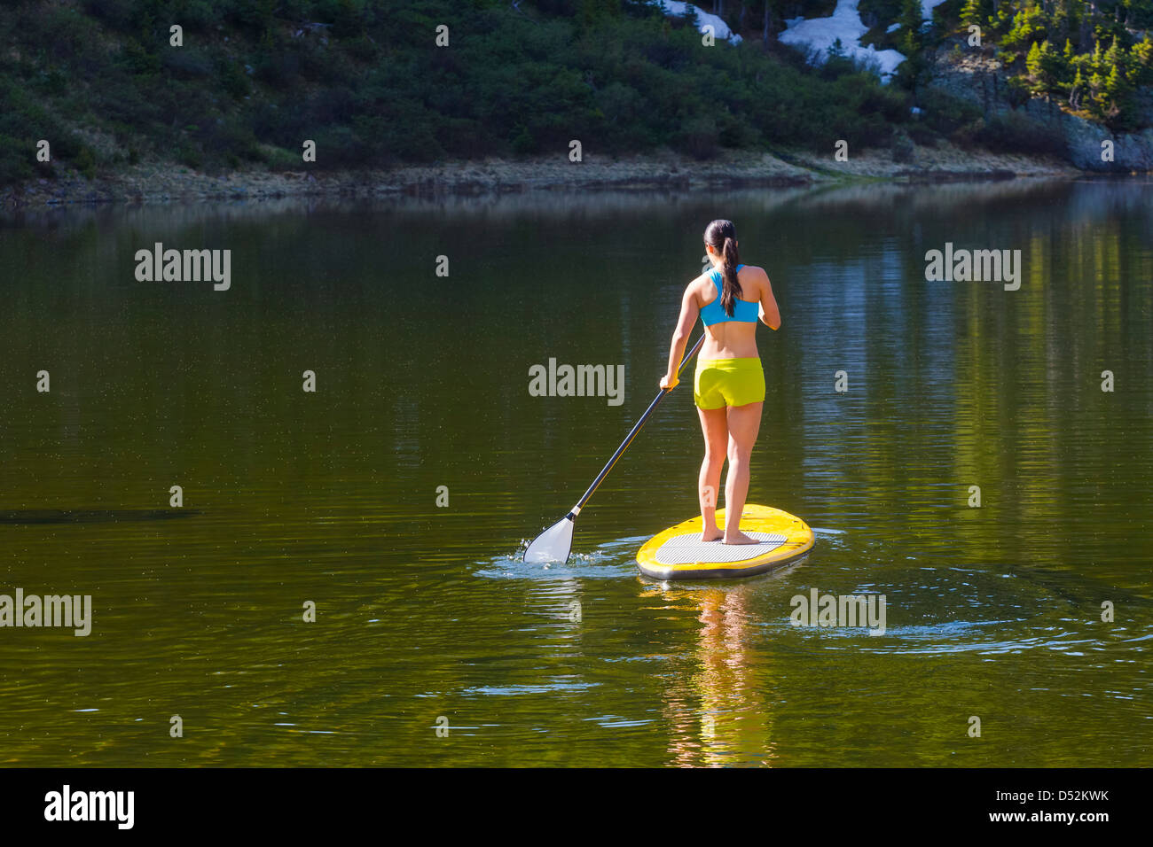Hispanic woman riding paddle board Banque D'Images
