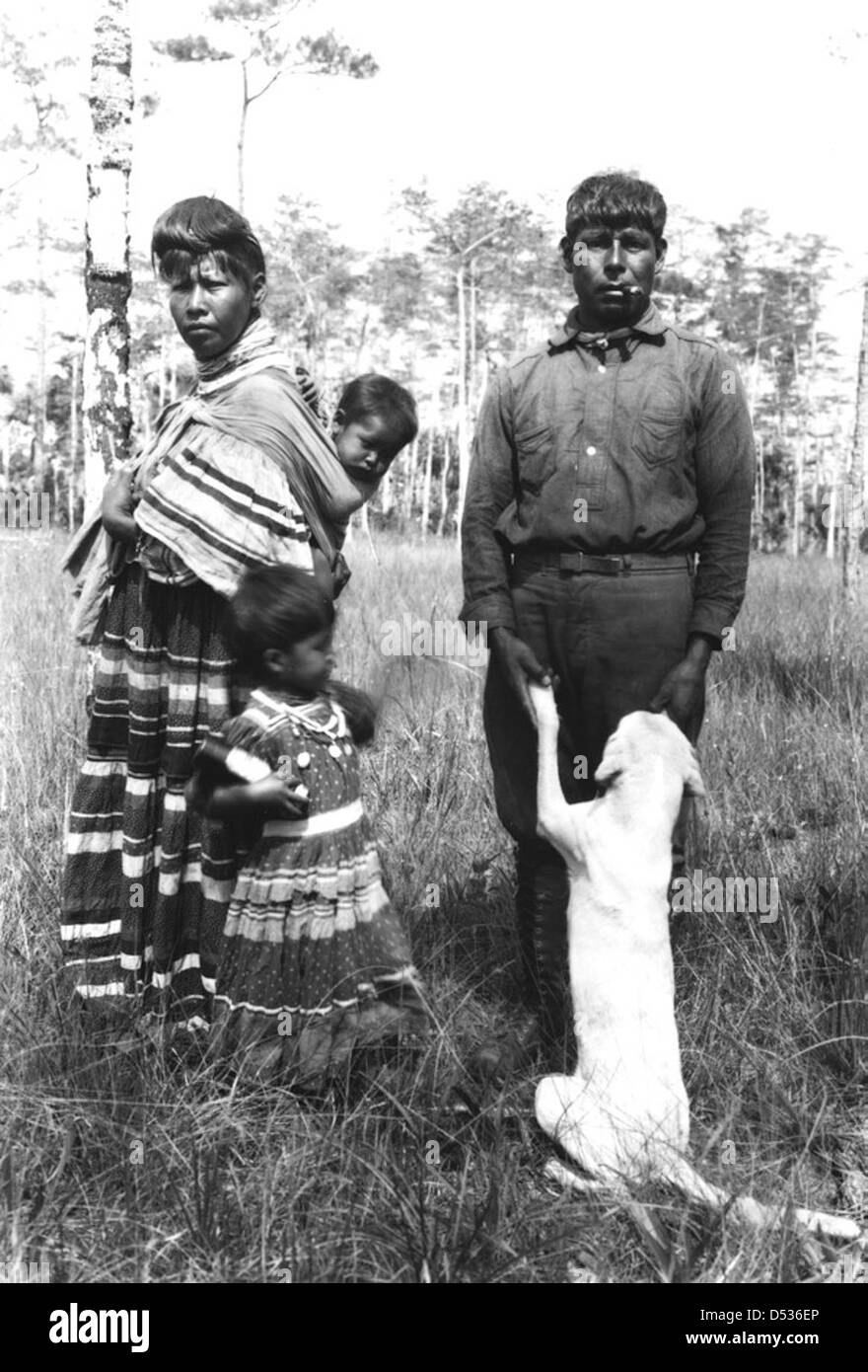 Josie Billie, une femme séminole, pose avec sa famille et son chien à Big Cypress Swamp, en Floride. Cette photographie historique, qui fait partie de la Bibliothèque d'État et des Archives de Floride, reflète la vie séminole dans la région. Banque D'Images
