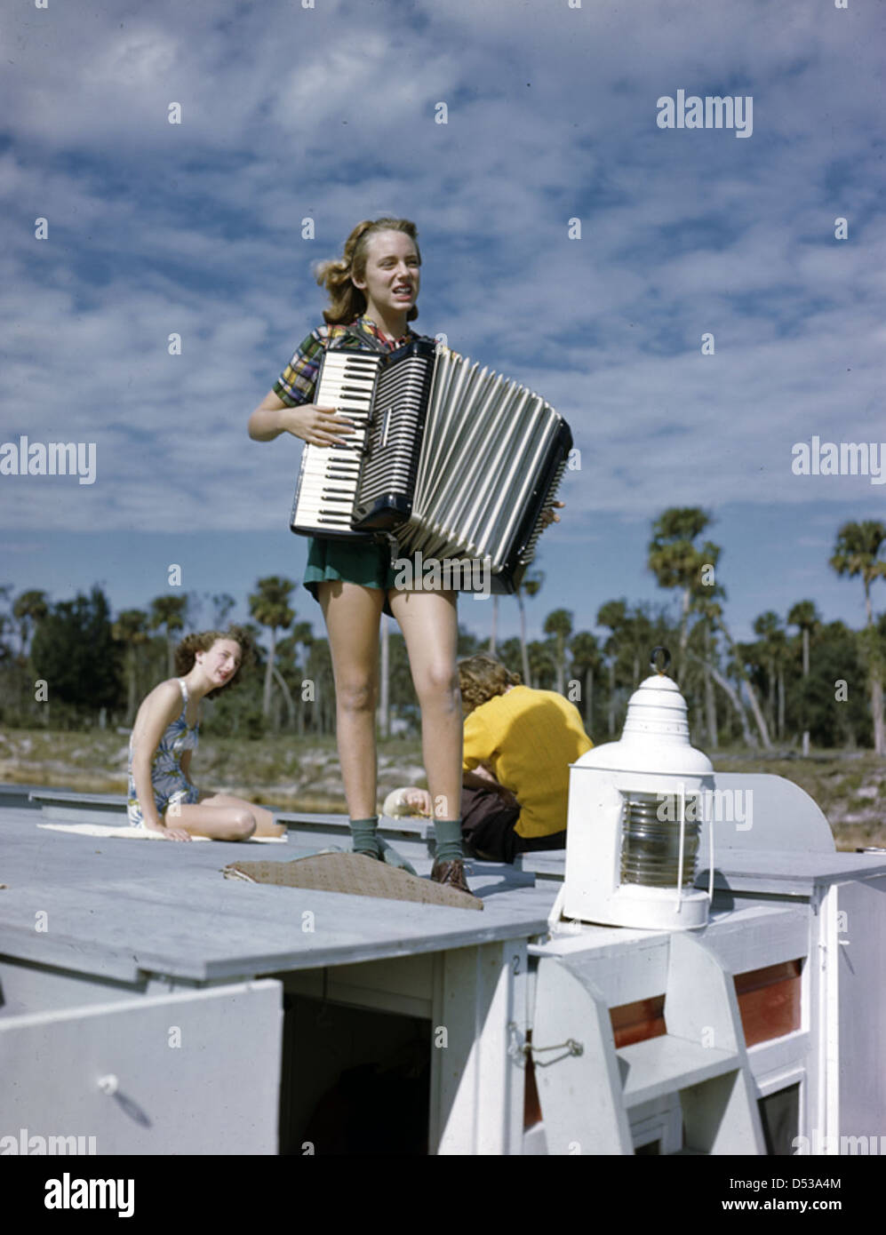 Lois Duncan Steinmetz joue de l'accordéon à bord des Lazy Bones, un canot sur la rivière Caloosahatchee à Fort Myers, en Floride, dans les années 1940, reflétant le style de vie des auteurs américains sur l'eau. Banque D'Images