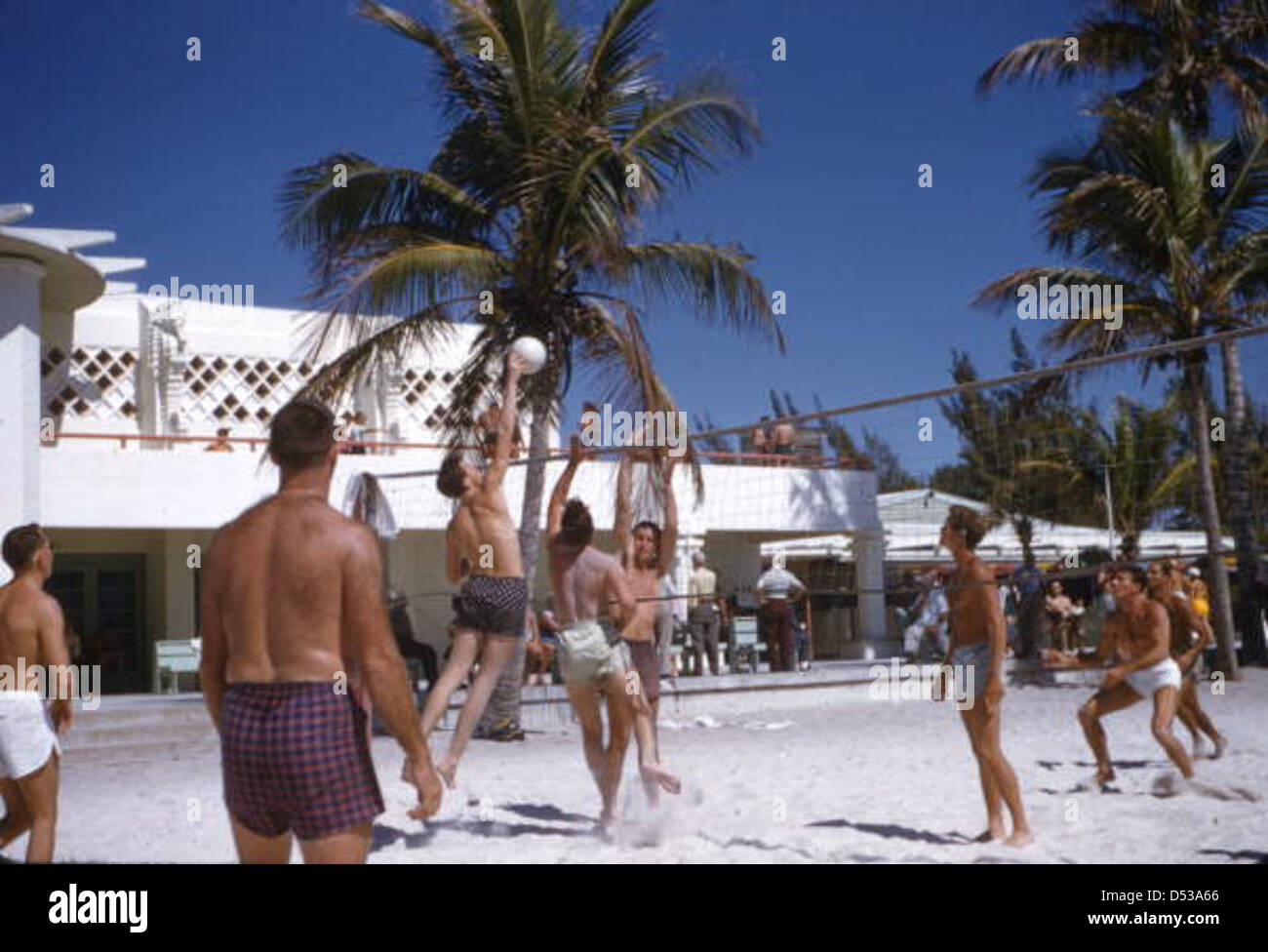 Les jeunes hommes jouent au volley-ball au Lido Beach Municipal Casino à Sarasota, en Floride, pendant les années 1950, reflétant la culture de plage récréative de l'époque. Banque D'Images