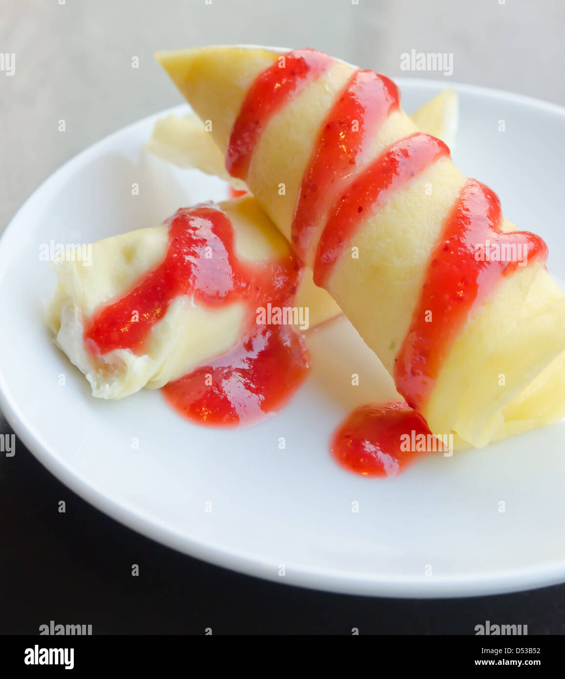 Rouleaux crêpe remplie de crème blanche , topping avec sirop de fraise Banque D'Images