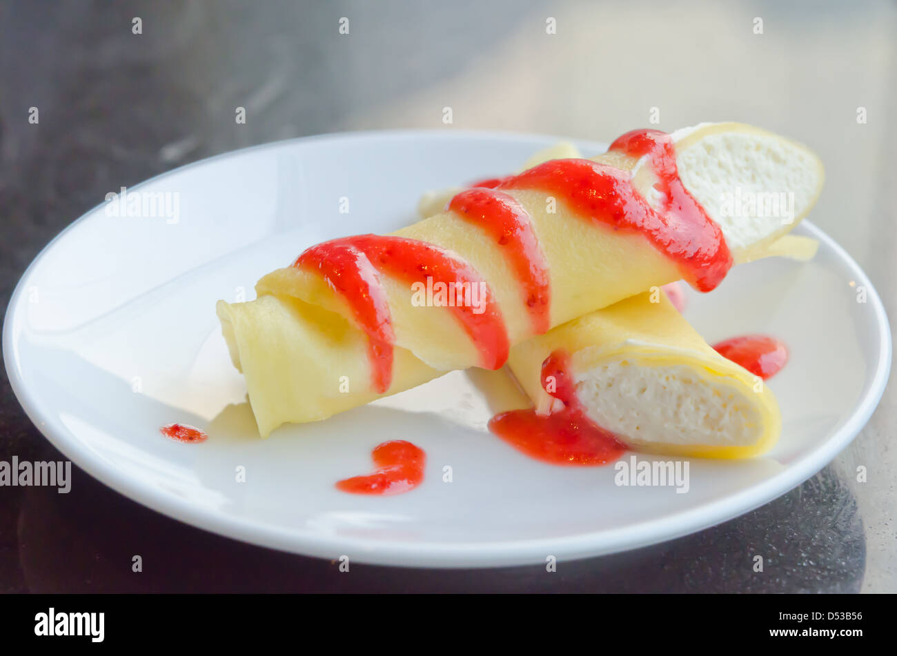 Rouleaux crêpe remplie de crème blanche , topping avec sauce aux fraises Banque D'Images