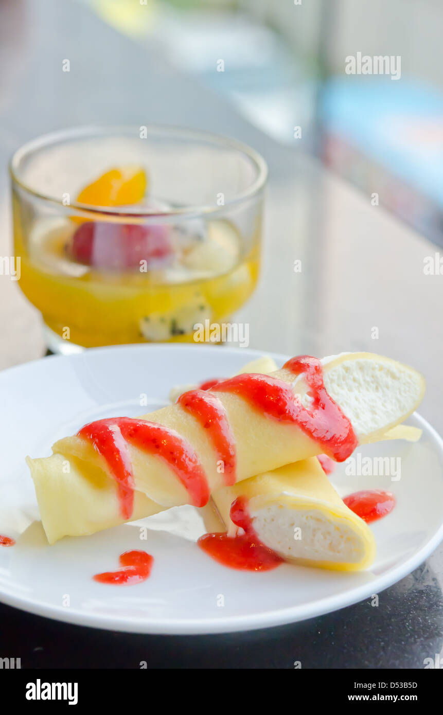 Le rouleau des Crêpes avec sirop de fraise et crème sur le plat et mélanger les fruits en dessert sur la table , verre Banque D'Images