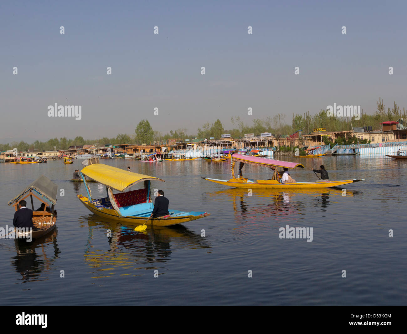 Plusieurs nombre de shikaras sur l'eau du lac Dal à Srinagar avec l'arrière-plan de péniches et ciel bleu Banque D'Images