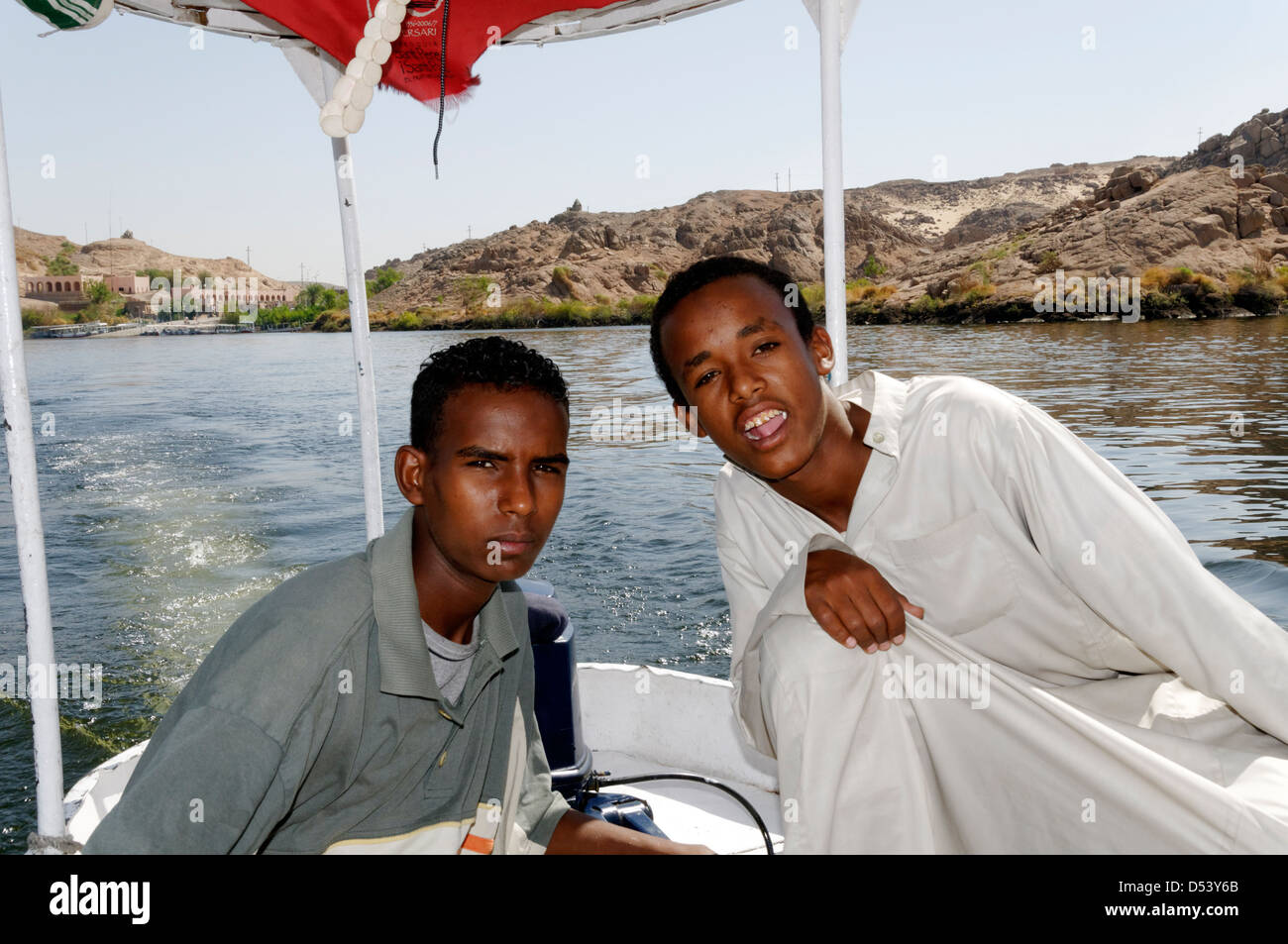 Aswan. L'Égypte. Garçon nubien adolescents l'exploitation d'un bateau touristique sur le Nil à l'île de Philae les temples. Banque D'Images