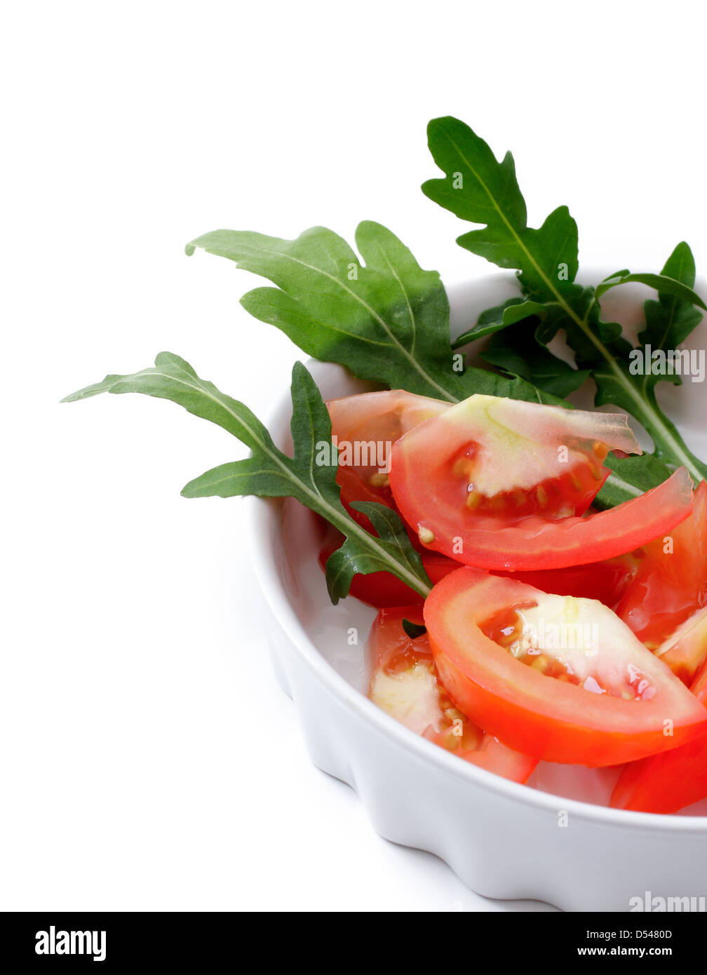 Tomates en salade de roquette dans une tasse blanche, studio isolated Banque D'Images