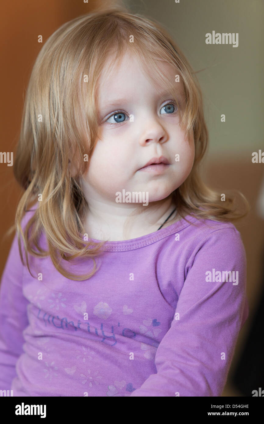 Photo de pensive petite fille aux yeux bleus et aux cheveux blonds Banque D'Images