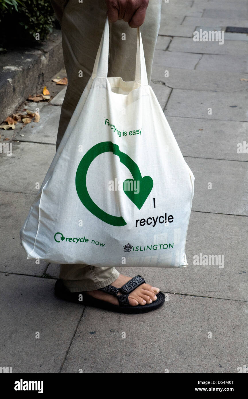 Homme tenant un sac de coton réutilisable Je recycle avec logo imprimé sur le côté. Banque D'Images