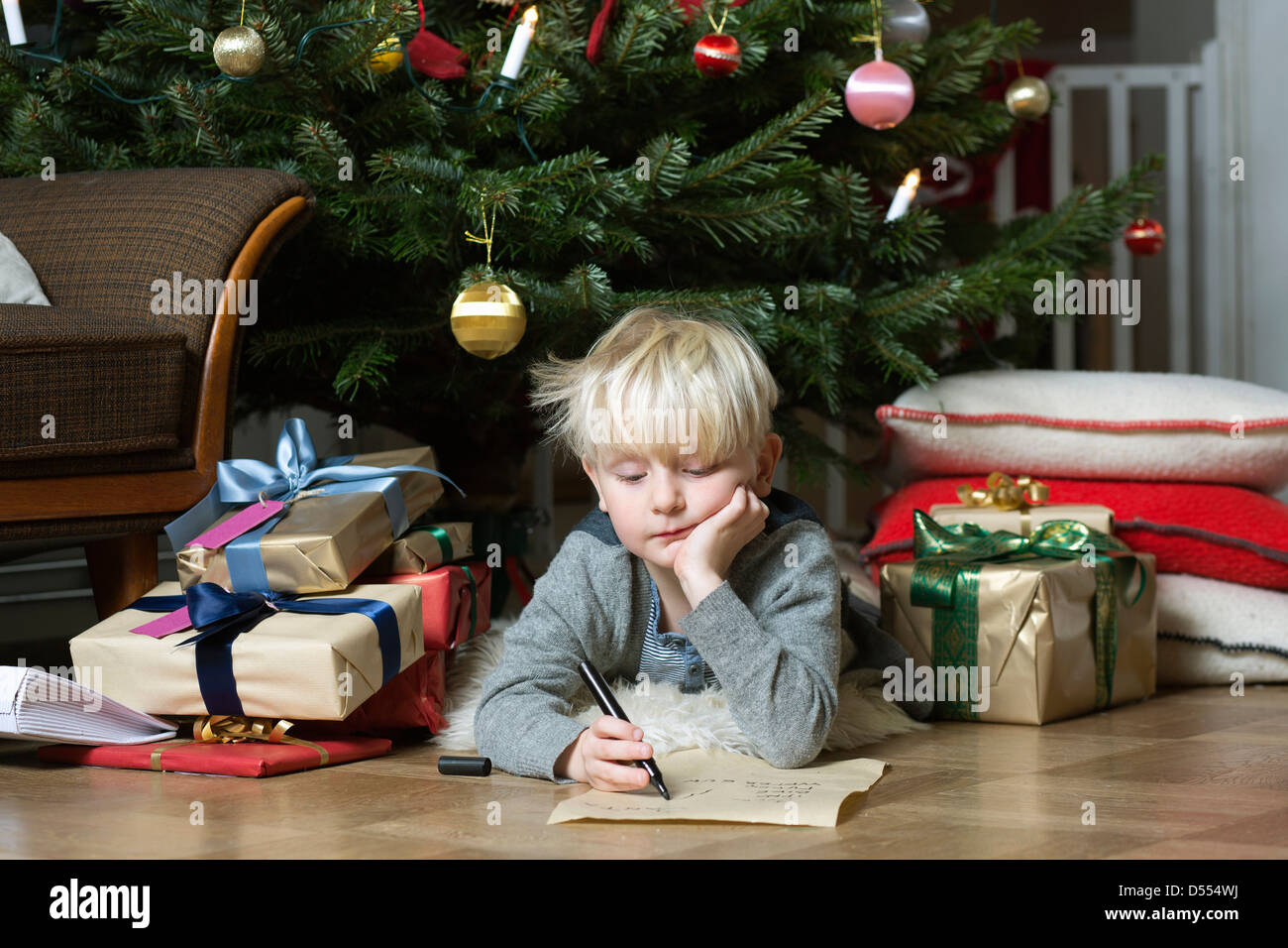 Garçon écrit en vertu de l'arbre de Noël Banque D'Images