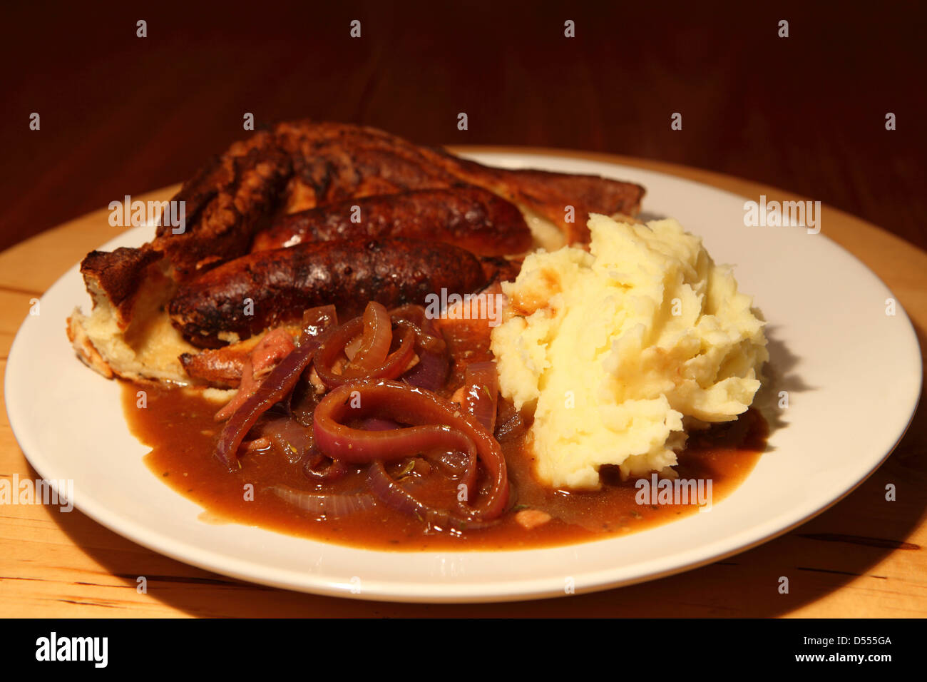 Toad dans le trou est servi avec sauce à l'oignon et la purée de pommes de terre. Banque D'Images